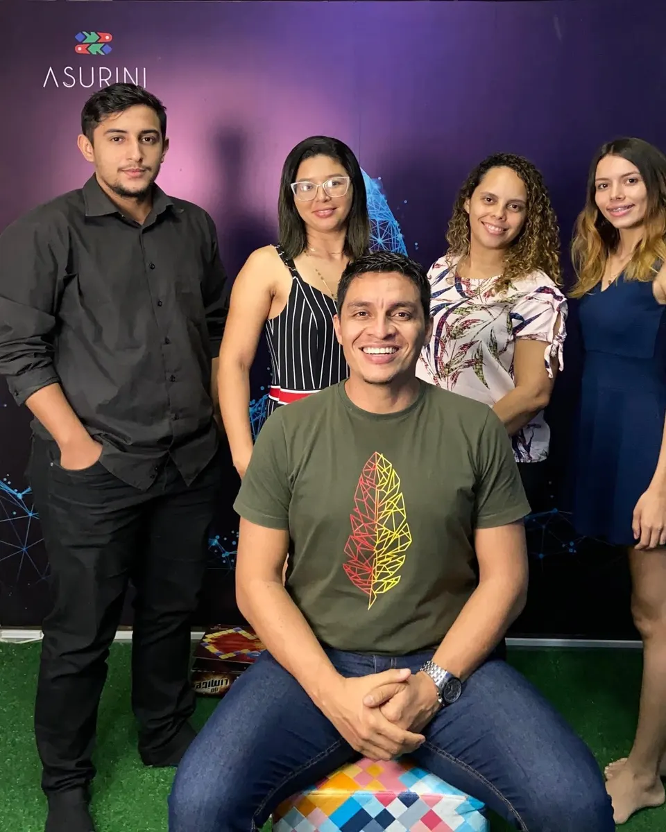 Jackson sentado à frente de quatro alunos sorridentes, diante de um painel roxo